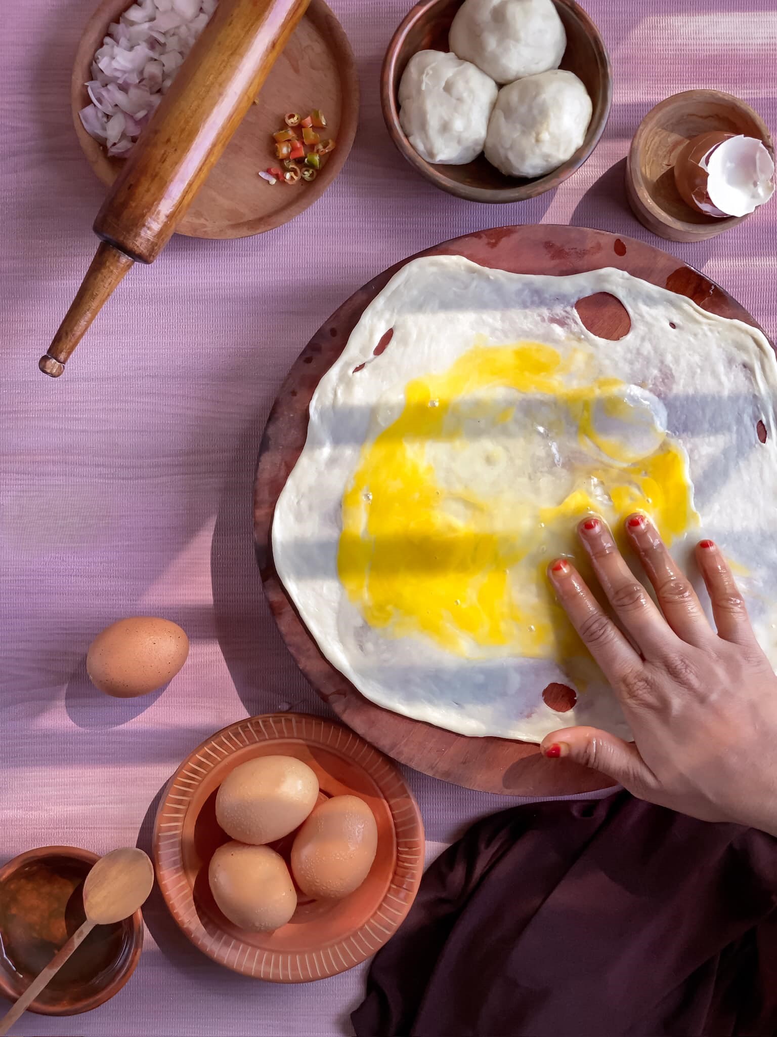 Female hands mixing an egg over dough